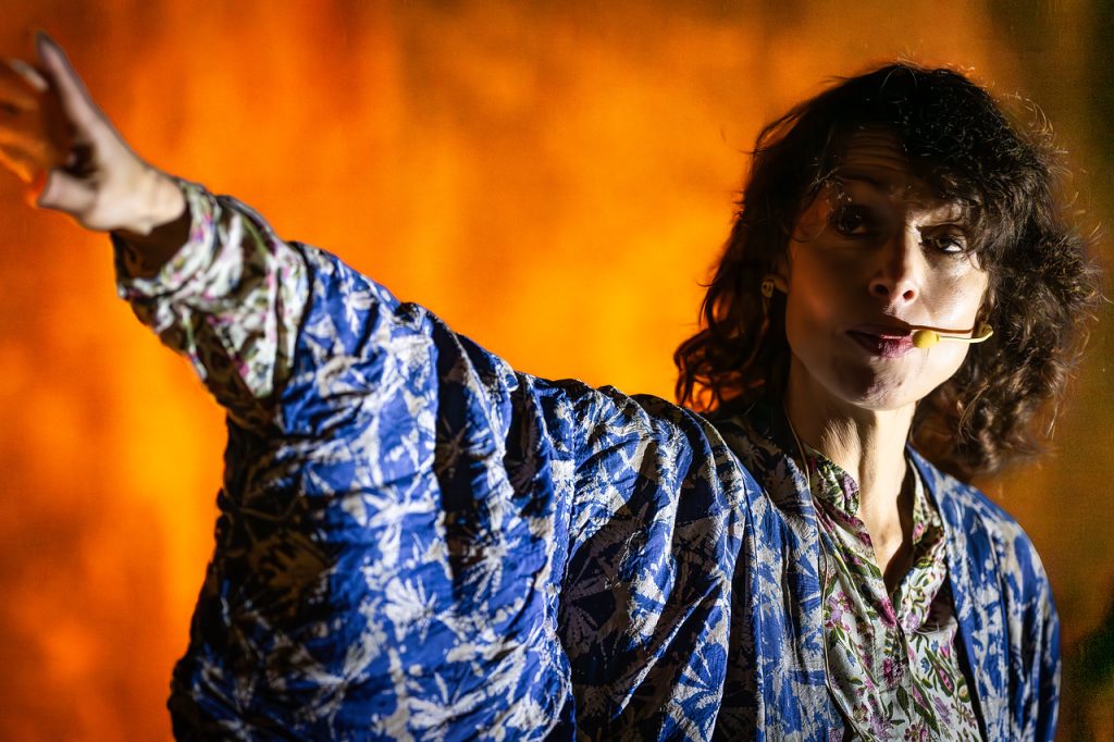 vanessa wearing a blue kimono against a gold background, she is telling a story