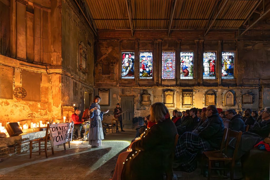 vanessa in a candlelit chapel with a band telling a story to adults
