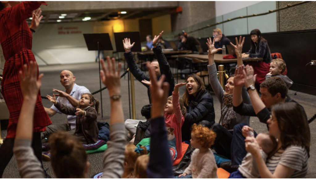 family groups sat on the floor, listening to vanessas story and lifting their hands to join in