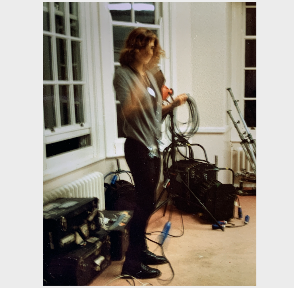 a picture of me in a crowded room full of lighting gear, I am coiling up a cable and look very young and happy