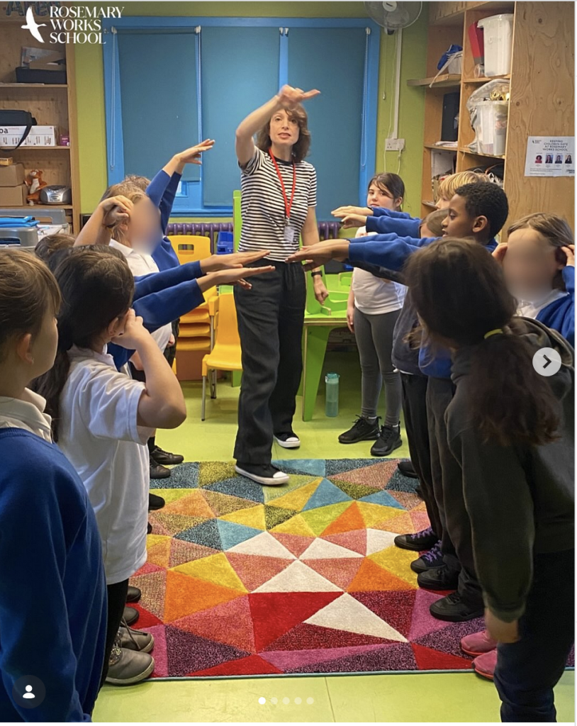 storyteller standing with kids on a colourful carpet